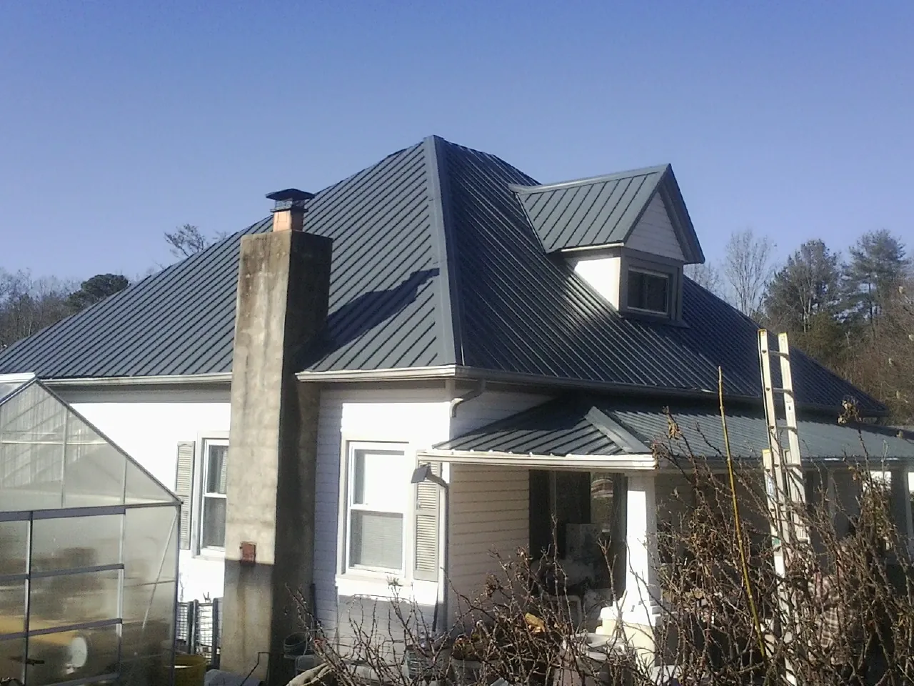 Dark blue standing seam metal roof on a white farmhouse with dormer — Slate & Tile Roof Repair by Roofing Brothers in Dingmans Ferry