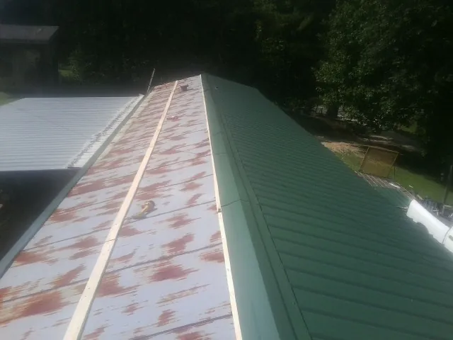 Old rusted panels beside newly installed green metal roofing — Wind Damage Roof Repair by Roofing Brothers in Dingmans Ferry