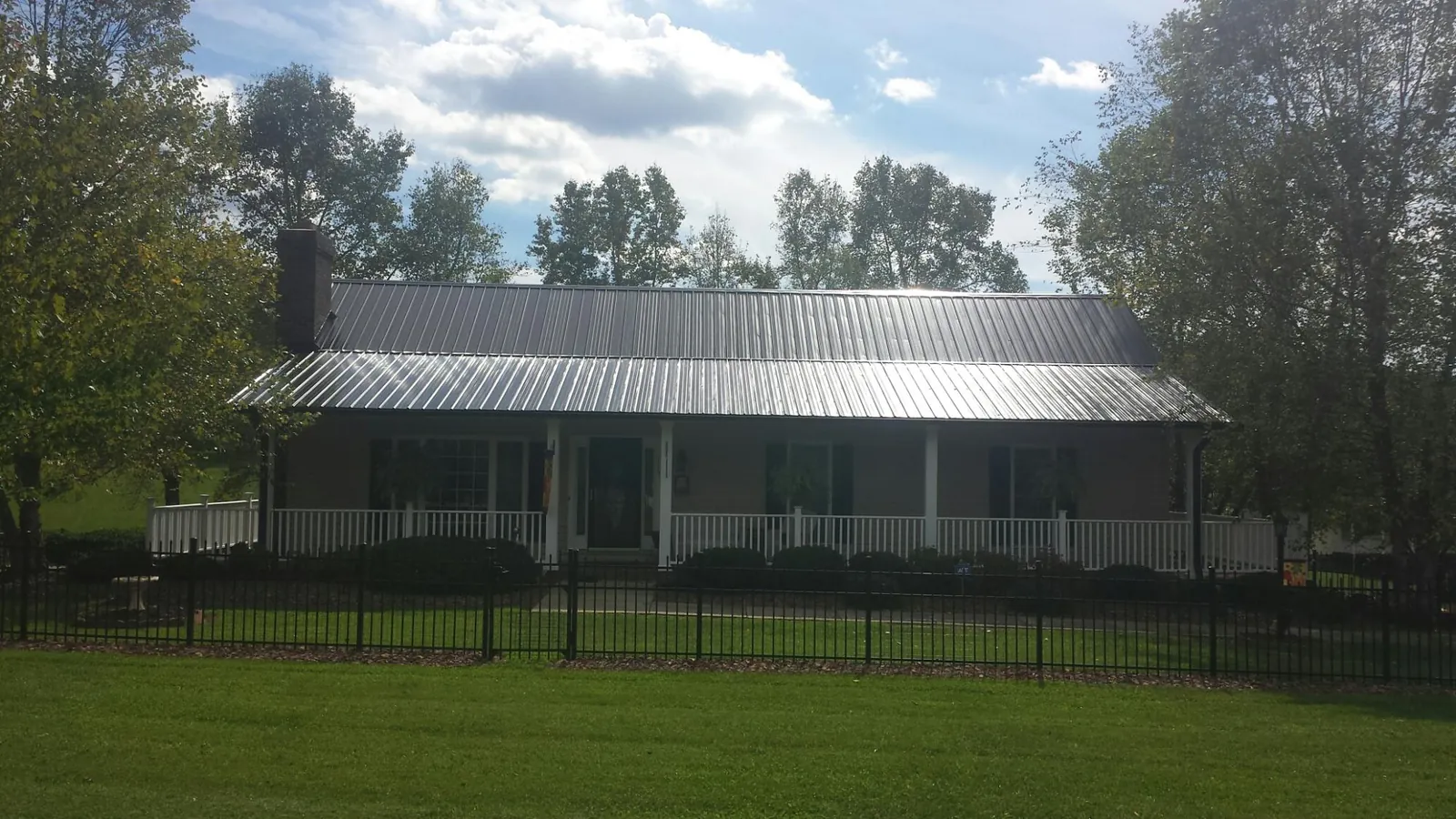 Gray metal roof on a brick ranch with a full width front porch — Gutter Guard Installation work by our crew in Dingmans Ferry