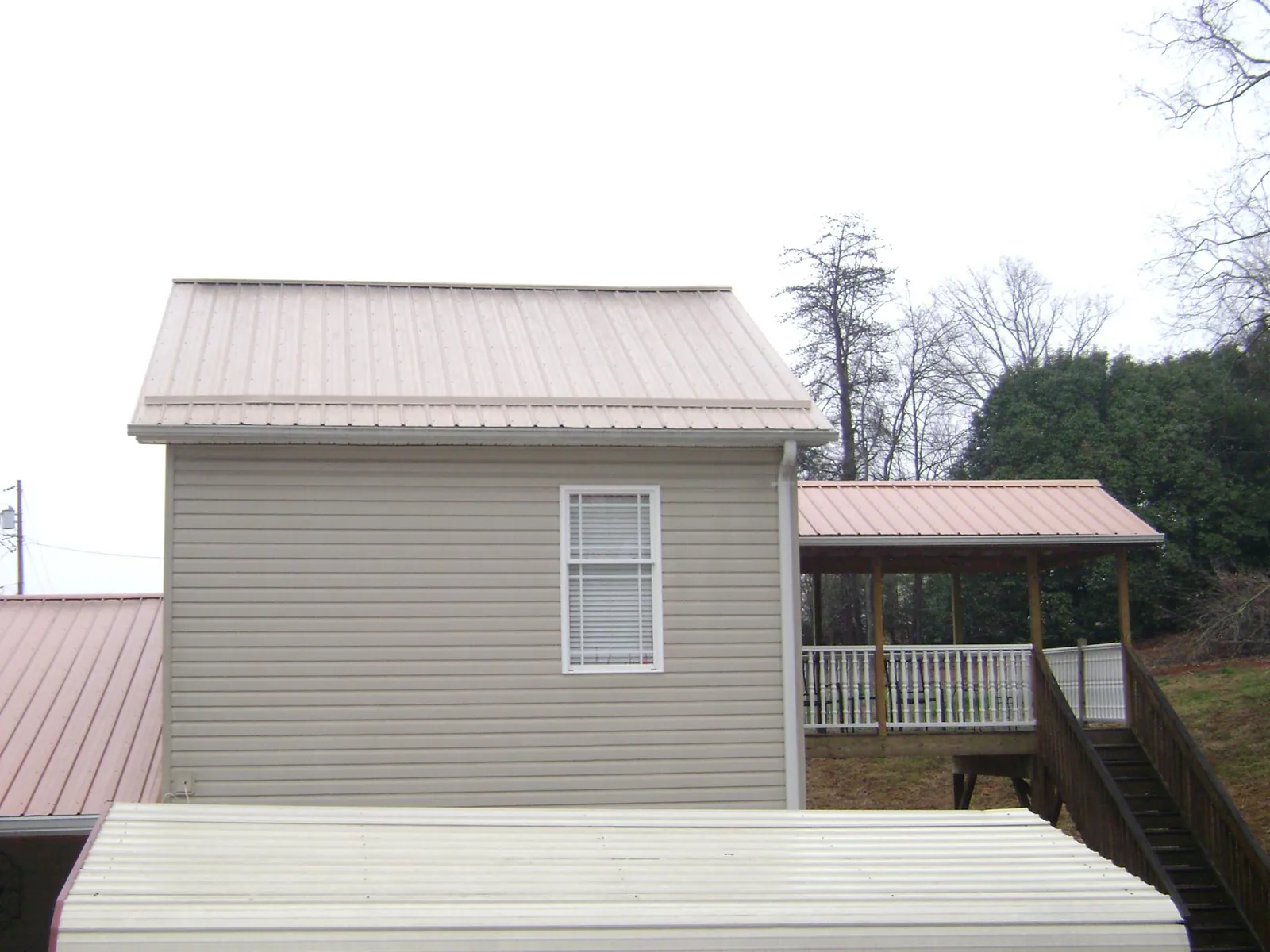 Tan metal roofs on a two story addition and attached porch, from a Roof Replacement job in Dingmans Ferry