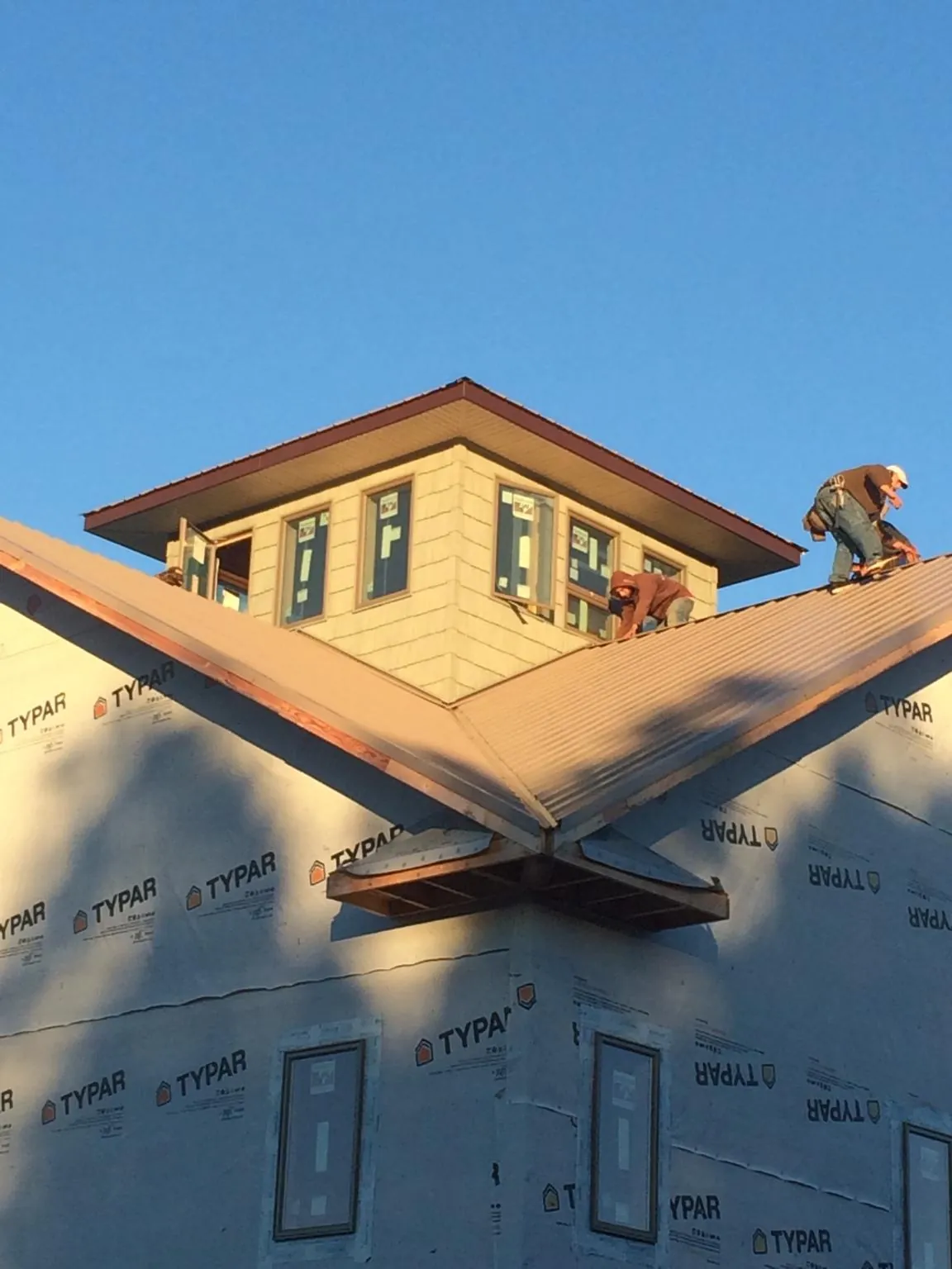 Roofers working around a rooftop cupola on a new metal roof at sunset — Roof Waterproofing in Dingmans Ferry by Roofing Brothers